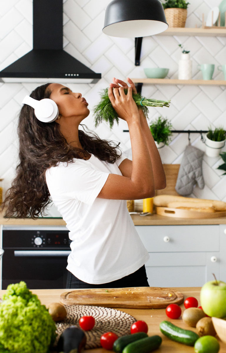 Contacto 1 Mujer cantando en la cocina con los cascos inalámbricos escuchando música